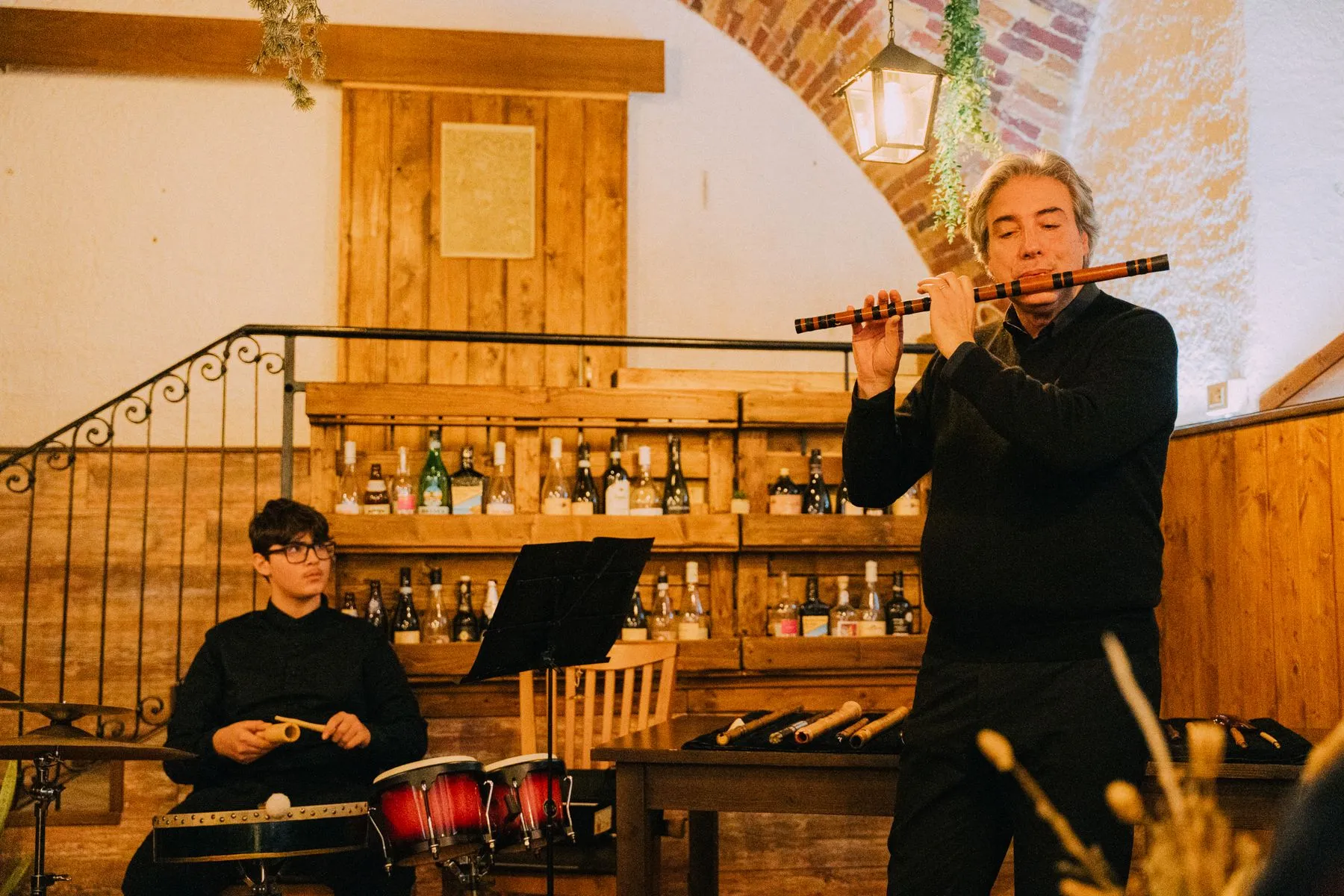 Il M° Marco Felicioni suona un flauto etnico nella sala, con il percussionista alle spalle