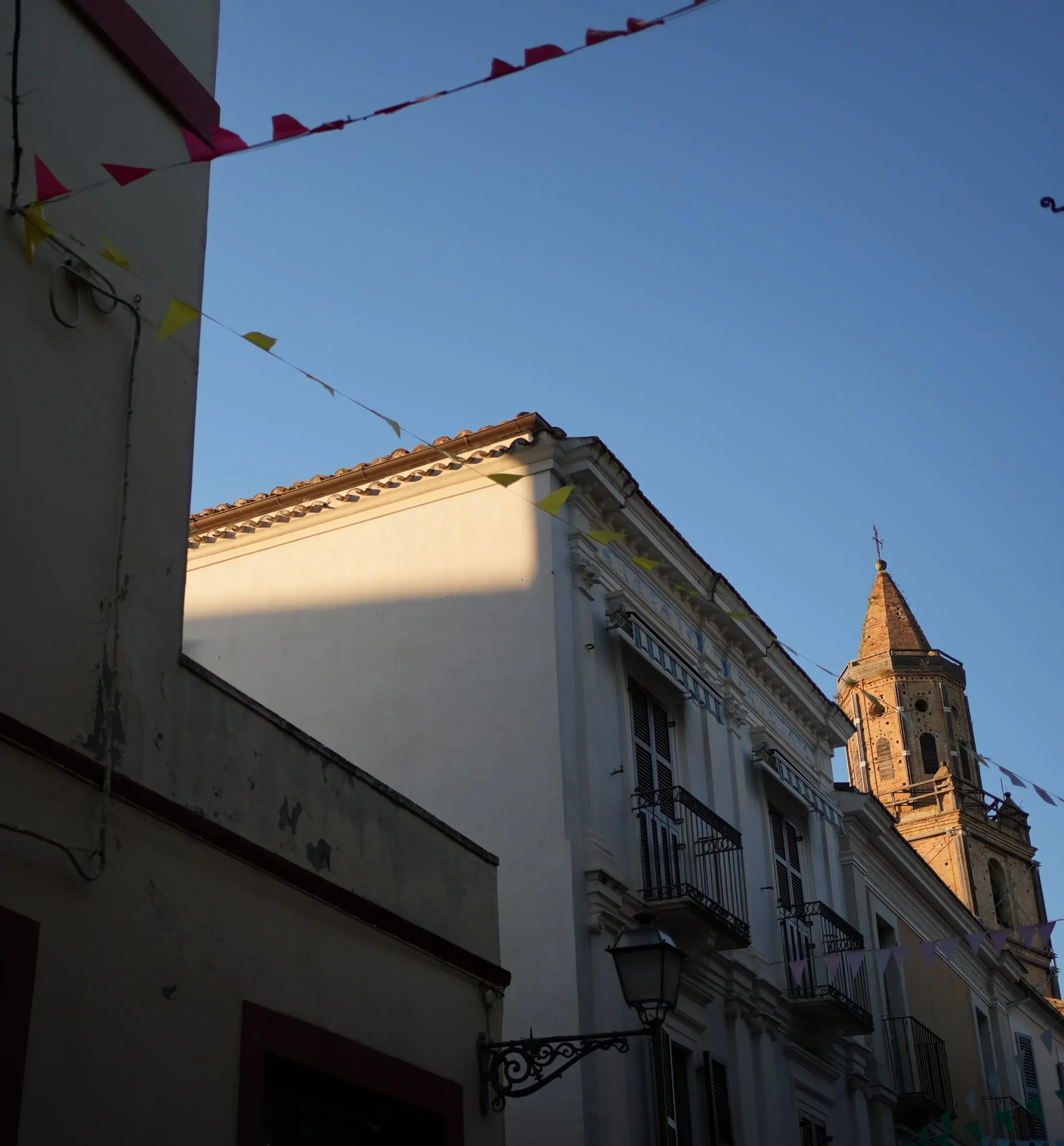 Il campanile di Città Sant'Angelo al tramonto, tra le bandierine della festa