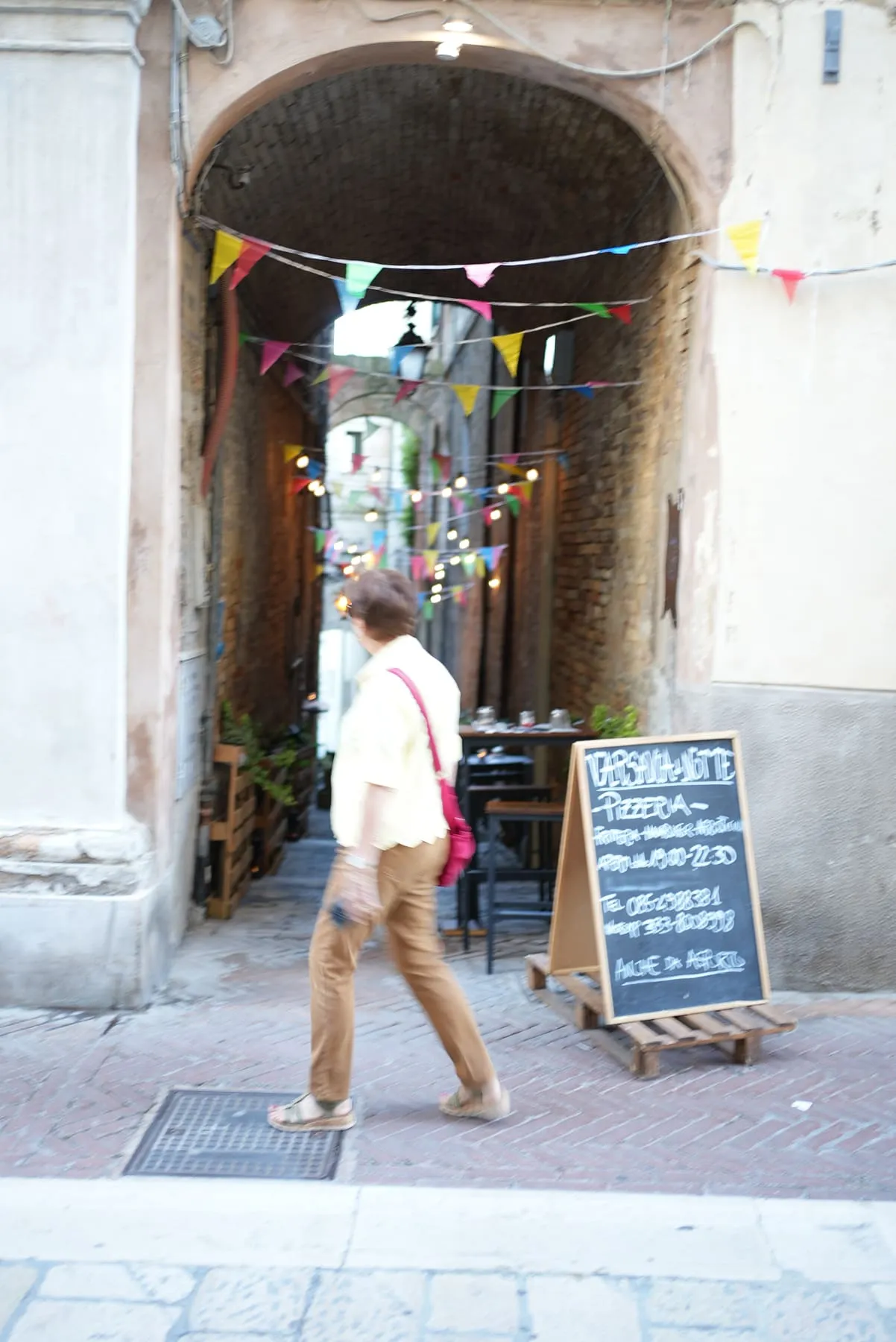 Qualcuno passa, mosso, nel vicolo del borgo